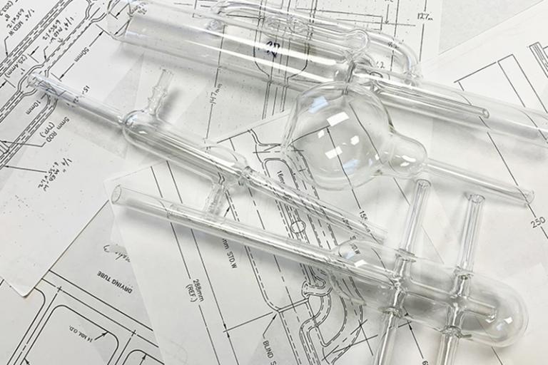 Scientific glass apparatus on top of technical drawings