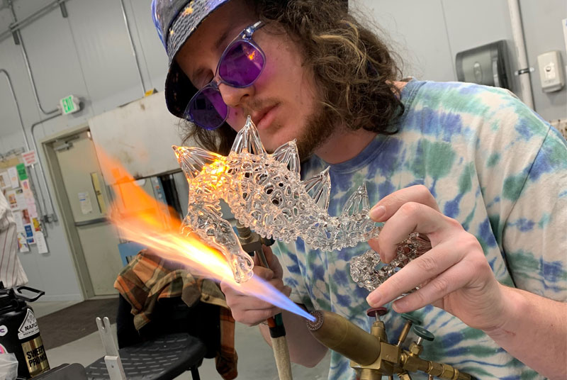Man creating a glass seahorse at a torch with a large flame
